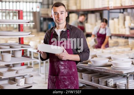 Enthusiastic ceramicist demonstrating handcrafted plates in ceramic studio Stock Photo