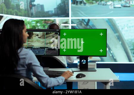 Indian employee works with isolated mockup screen and monitoring traffic, using city surveillance real time footage via satellite radar and CCTV cameras. Young woman following urban activity. Stock Photo