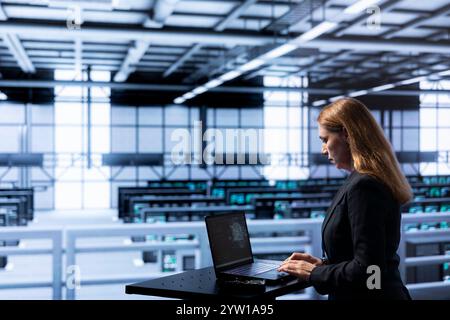 Admin in data center using laptop to visualize artificial intelligence neural networks made up of interconnected nodes. Supervisor oversees AI systems processing information Stock Photo