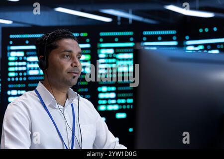 Developer using computer to troubleshoot hardware and software errors in server farm. Man in high tech facility implementing and maintaining server and network infrastructure in data center Stock Photo