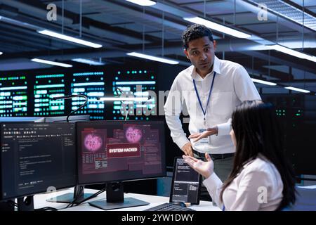 Programmers doing teamwork in server hub trying to protect hardware from hacker stealing information. Colleagues in data center workspace trying to fix security breach alert caused by virus Stock Photo