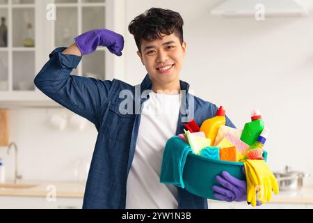 Positive asian guy with cleaning supplies showing muscles Stock Photo