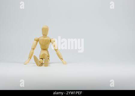 Wooden figure representing a sitting position on the floor denoting rest and relaxation after an activity. Stock Photo