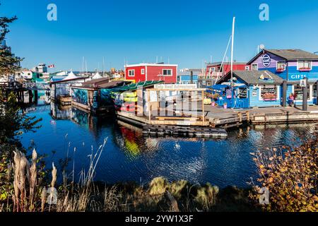 A group of colorful houses are docked in a harbor. The houses are painted in bright colors and are surrounded by water. The scene is lively and cheerf Stock Photo