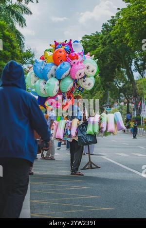 Balikpapan, Indonesia - November 9th, 2024.  Besides balloons, he is also selling cotton candy. Stock Photo