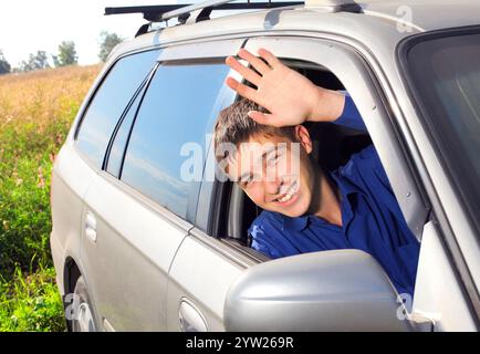 happy young man sit in the car and give salute gesture Stock Photo
