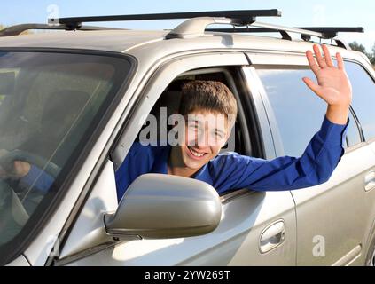 happy young man sit in the car and give salute gesture Stock Photo