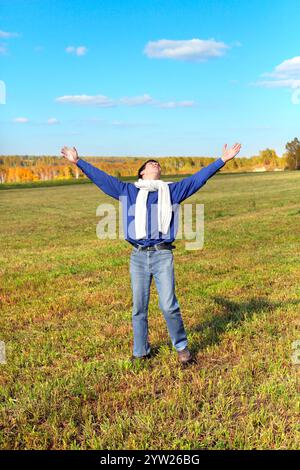 man on autumn field rising up his hands Stock Photo
