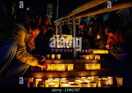 Nijmegen, Netherlands. 08th Dec, 2024. People are seen fighting the wind and putting candles inside paper cups in commemoration of World Candle Day. Around 18,000 candles were lit to remember all deceased children in the Palestine-Israel-Lebanon region. The candles were placed along the stairs leading to the quay on the Waal in Nijmegen. At the same time, the names of the children who died in the war in the past year were read by people attending the event. Credit: SOPA Images Limited/Alamy Live News Stock Photo