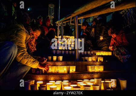 Nijmegen, Netherlands. 08th Dec, 2024. People are seen fighting the wind and putting candles inside paper cups in commemoration of World Candle Day. Around 18,000 candles were lit to remember all deceased children in the Palestine-Israel-Lebanon region. The candles were placed along the stairs leading to the quay on the Waal in Nijmegen. At the same time, the names of the children who died in the war in the past year were read by people attending the event. (Photo by Ana Fernandez/SOPA Images/Sipa USA) Credit: Sipa USA/Alamy Live News Stock Photo