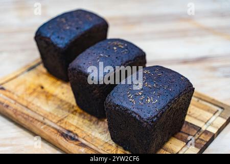 Three loaves of caraway rye bread on a wooden cutting board in the bakery. High quality photo Stock Photo