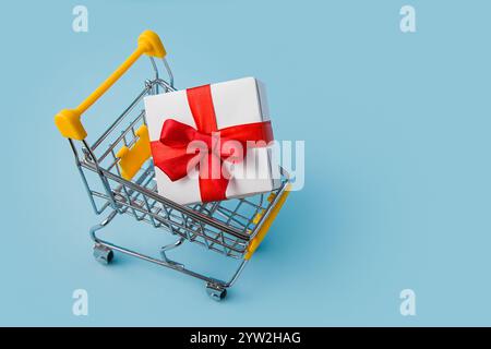 Shopping Cart with Big Gift Box on Blue background. Christmas Shopping Concept. Online shopping concept Stock Photo
