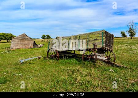 A wooden wagon is parked in a field next to a small building. The scene is peaceful and quiet, with the wagon and building being the only visible obje Stock Photo