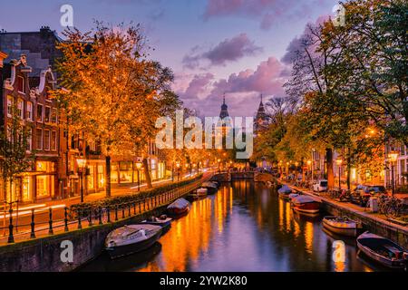 As twilight descends on Amsterdam, the charming canals reflect the golden hues of autumn trees. Shops glow warmly while boats float serenely, Christma Stock Photo