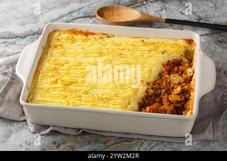 Homemade vegan shepherd's pie with lentils, onions, mushrooms, tomatoes, carrots close-up in a baking dish on the table. Horizontal Stock Photo