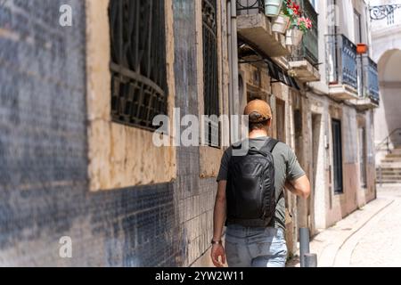 Traveler man walks through the old town of Lisbon. Stock Photo