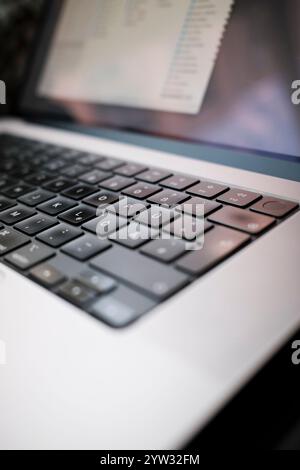 Close-up of a modern laptop keyboard with a blurred screen in the background. Stock Photo