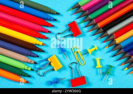 Various colorful markers and stationery items are scattered on a blue surface, showcasing vibrant tools for creativity and organization. Stock Photo