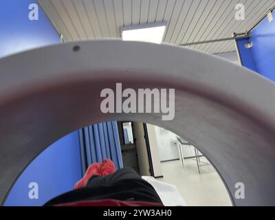 A person is laying on a machine with a red stripe on it. The machine is in a hospital room Stock Photo
