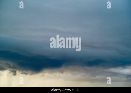 Dark storm clouds gather, indicating an approaching storm, with lighter clouds and a hint of sunset below, Norway Stock Photo