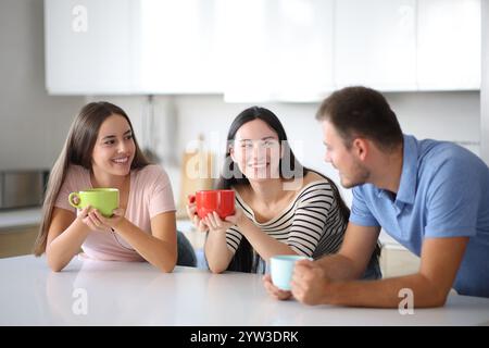 Three roommates talking at breakfast in the kitchen at home Stock Photo