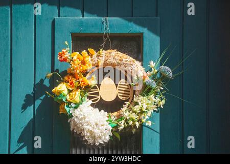 Floral wreath with Easter eggs and the inscription “Happy Easter” on a wooden door, Germany Stock Photo
