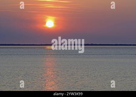 Sunset over the North Sea at low tide, the outline of the island of Juist on the horizon, Norddeich, Lower Saxony, Germany, Europe Stock Photo