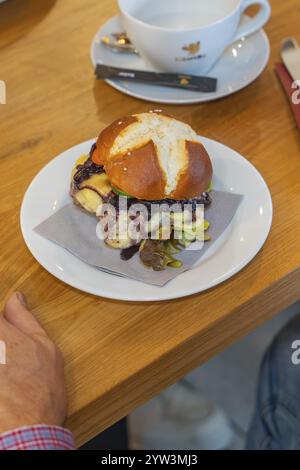 A burger on a pretzel bun with a napkin on a plate, autumn creations, Cafe Kuh, Deckenpfronn, Black Forest, Germany, Europe Stock Photo