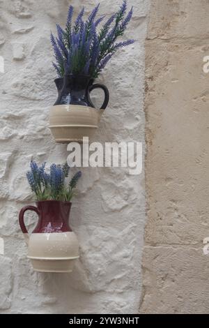 Jugs with artificial flowers hanging as decoration on a white house wall, Cisternino, southern Italy, Italy, Europe Stock Photo