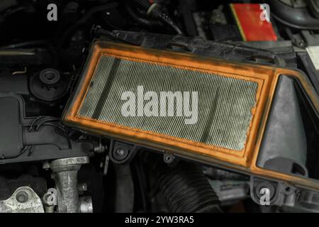 Old used air filter in dirt and dust to clean the air. Dirty car engine air filter to be replaced due to contamination. Stock Photo