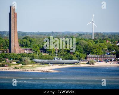 72 metre (236 ft) Laboe Naval Memorial and U-Boat 995 museum ship with paddle boarders in the foreground and a large wind turbine in the background. Stock Photo