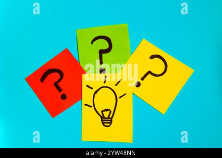 Top view of sticky papers with question marks and drawn idea bulb on blue background, concept of question and ideas Stock Photo