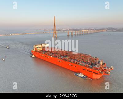 (241209) -- NANJING, Dec. 9, 2024 (Xinhua) -- This aerial drone photo taken on Dec. 9, 2024 shows the 'NGUYA FLNG,' a floating liquified natural gas (FLNG) facility, being tugged through the Sutong (Suzhou-Nantong) Bridge across the Yangtze River in east China's Jiangsu Province. The 'NGUYA FLNG,' the first large-scale FLNG facility made in the country, was transferred from Nantong of Jiangsu to Zhoushan of Zhejiang (both in east China), where it will be further assembled, integrated and modulated. An FLNG facility is capable of directly liquifying and storing natural gas harvested from an o Stock Photo