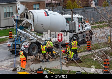 Workers pour concrete from a large concrete mixer into the formwork Stock Photo