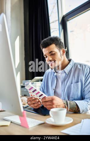 A stylish man examines color swatches thoughtfully at his desk in a modern office setting. Stock Photo
