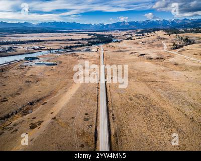 Highway aerial looking down shot of straight road leading towards the Canadian Rocky Mountains overlooking the small town of Morley Alberta Canada. Stock Photo