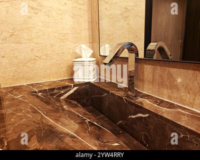 Sleek marble countertop features a polished sink and contemporary faucet in a luxurious bathroom setting. Stock Photo
