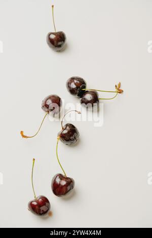 Scattered cherries with stems on a white surface, captured from above. Minimalistic top view emphasizes the simplicity, natural freshness, and vibrant Stock Photo