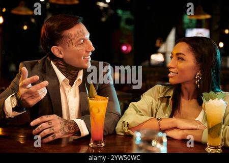 A young multicultural couple shares laughter and cocktails during a lively evening at the bar. Stock Photo
