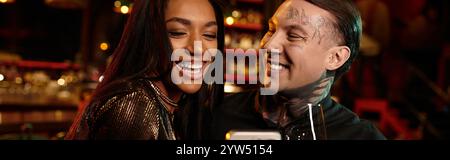 Young couple shares a joyful moment during their night out at a lively bar filled with excitement. Stock Photo