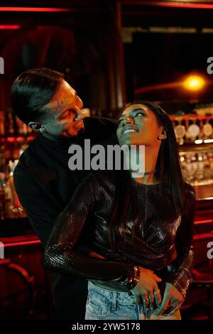 Young couple shares laughter and connection on a lively night out together at a bar. Stock Photo