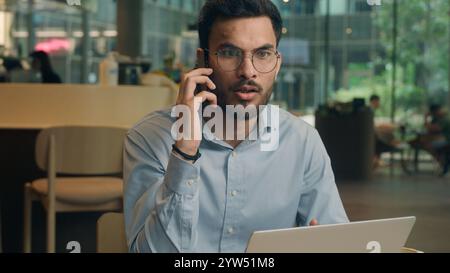 Indian man business guy Arabian businessman male freelancer visitor client in cafe restaurant freelance work answer mobile phone call stress upset Stock Photo