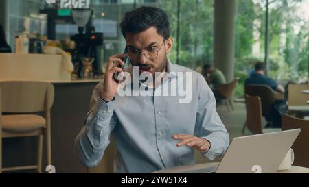 Indian man business guy Arabian businessman male freelancer visitor client in cafe restaurant freelance work answer mobile phone call stress upset Stock Photo