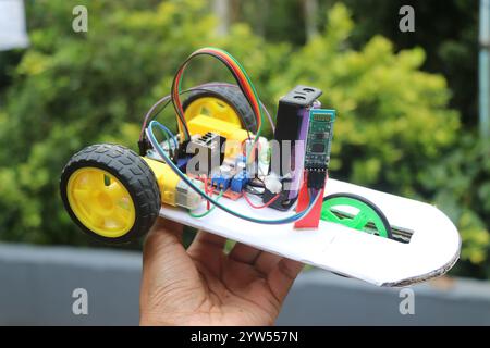 Bluetooth controlled robot car held in the hand on a natural background. Mini robotic car controlled wirelessly Stock Photo