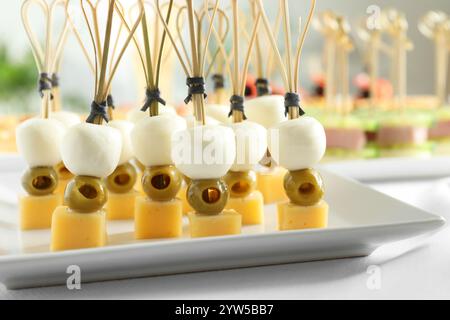 Tasty canapes with different types of cheese and green olives on white table, closeup Stock Photo