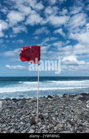 Red flag on rocky beach Stock Photo