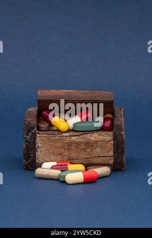 Wooden box overflowing with pills, tablets Stock Photo