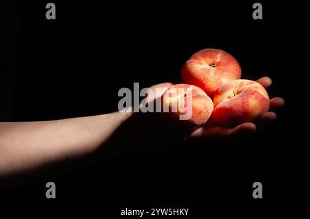 flat saturn peach in hand on black background Stock Photo