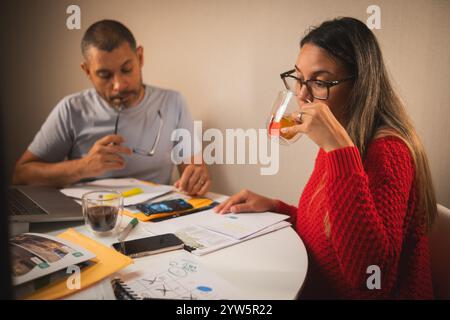 A man and a woman are sitting at a table with a laptop and a cell phone, couple organizing credit documents .New home concept. Stock Photo