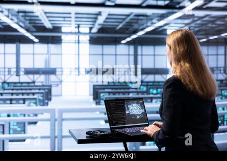 IT expert in data center updating AI systems, writing intricate binary code scripts on laptop. Certified admin using programming to upgrade artificial intelligence simulation model Stock Photo